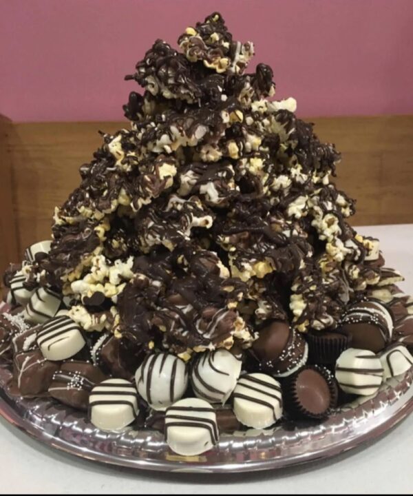 A chocolate covered cake with popcorn and candy.