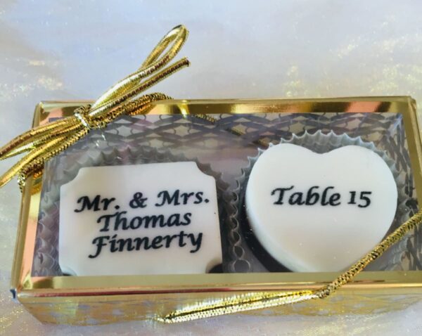 A box of wedding favors with the names and table numbers on top.