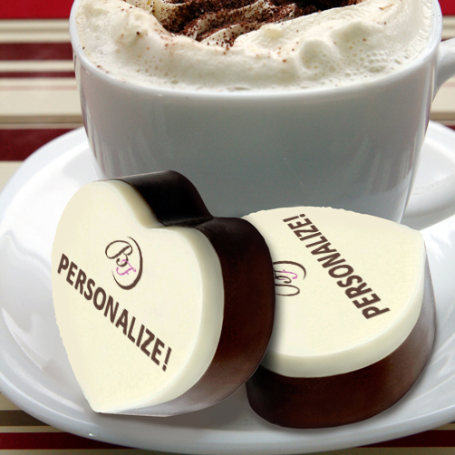 A cup of coffee and two chocolate hearts on a plate.